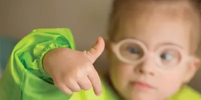 A young child wearing glasses reaching out during a play session